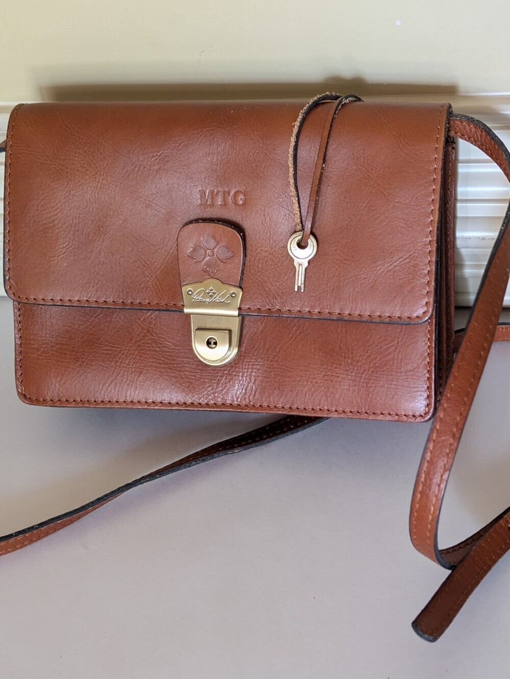 Patricia Nash Lanza Crossbody Organizer featuring a front metal buckle and a key